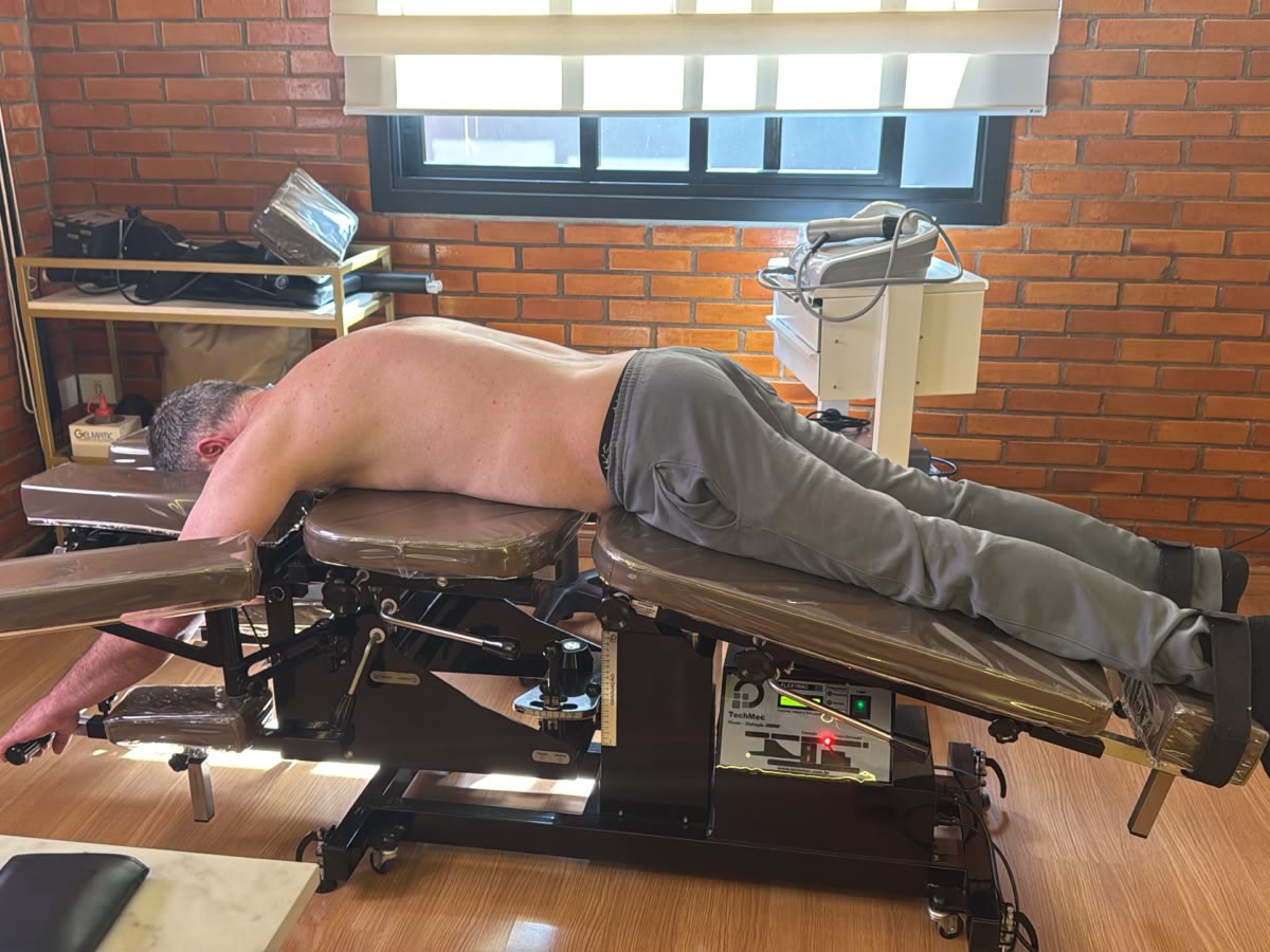 Paciente deitado de bruços na mesa de flexo-distração durante o tratamento da coluna lombar