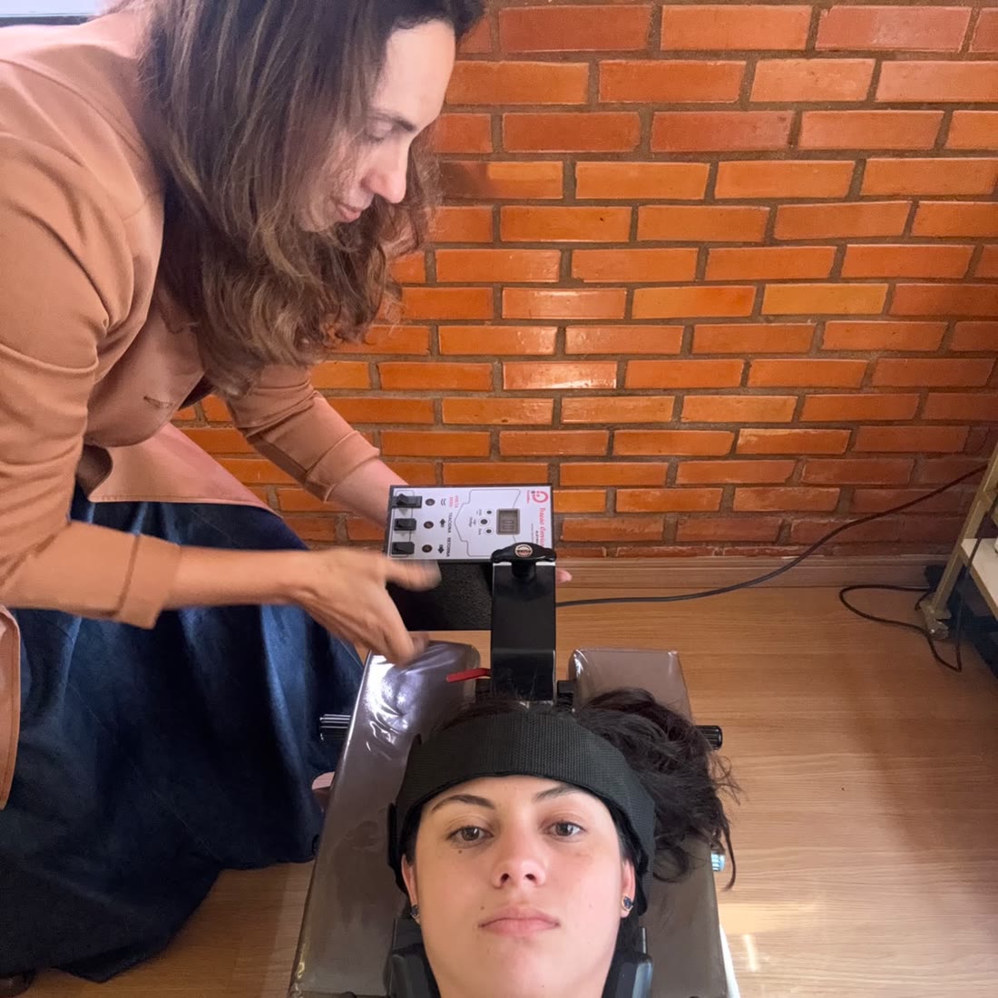Dra. Celiane ajustando o equipamento de tração cervical com a paciente deitada na maca